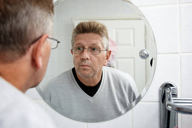 istock Man in the bathroom mirror examining stubble 530468215