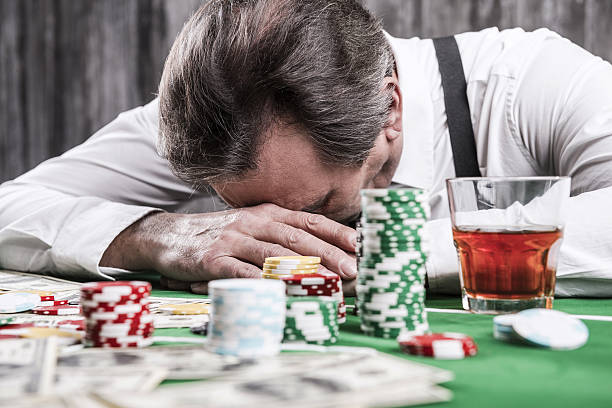 It is not my day. Depressed senior man in shirt and suspenders leaning his head at the poker table with money and gambling chips laying all around him texas hold em photos stock pictures, royalty-free photos & images