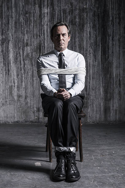 Feeling hopeless. Shocked businessman sitting at the chair and shouting while being tied up hostage photos stock pictures, royalty-free photos & images