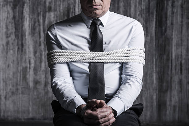 Fear and hopelessness. Cropped image of tied up businessman sitting at the chair with dirty wall  in the background hostage photos stock pictures, royalty-free photos & images