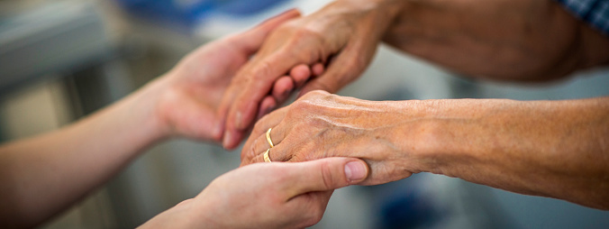Close up of a young woman's hands holding a senior woman's hands.