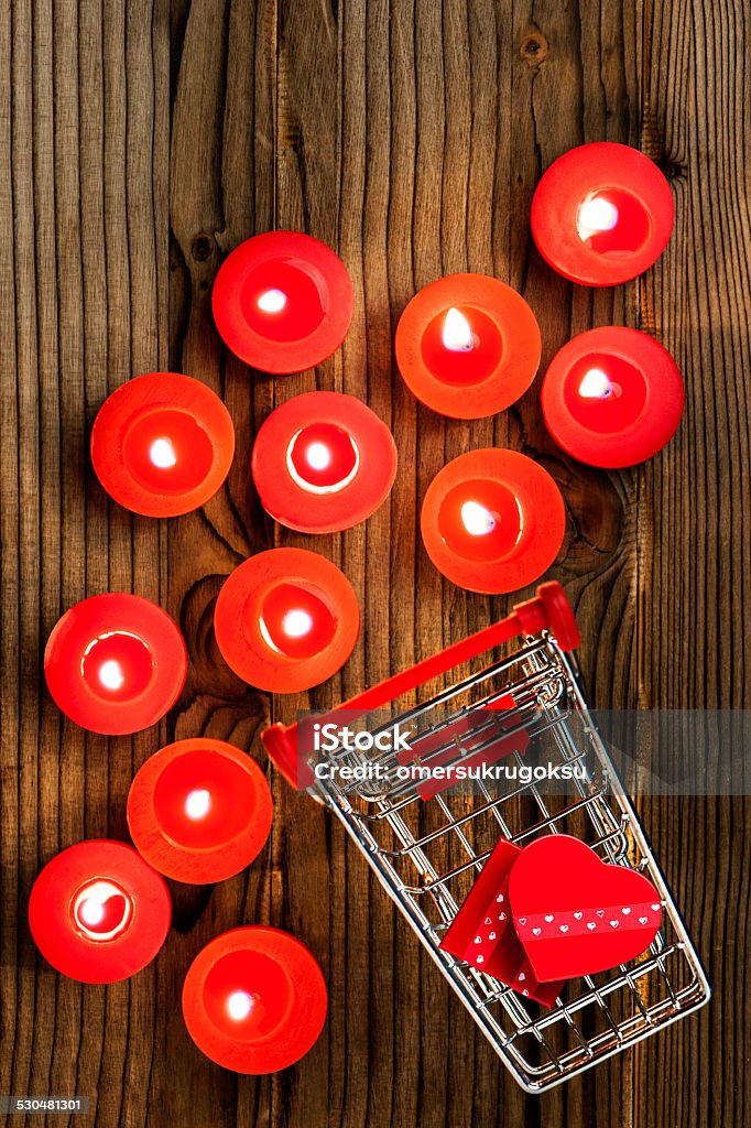 Shopping Cart Miniature shopping cart with red candles on wooden background. Birthday Stock Photo