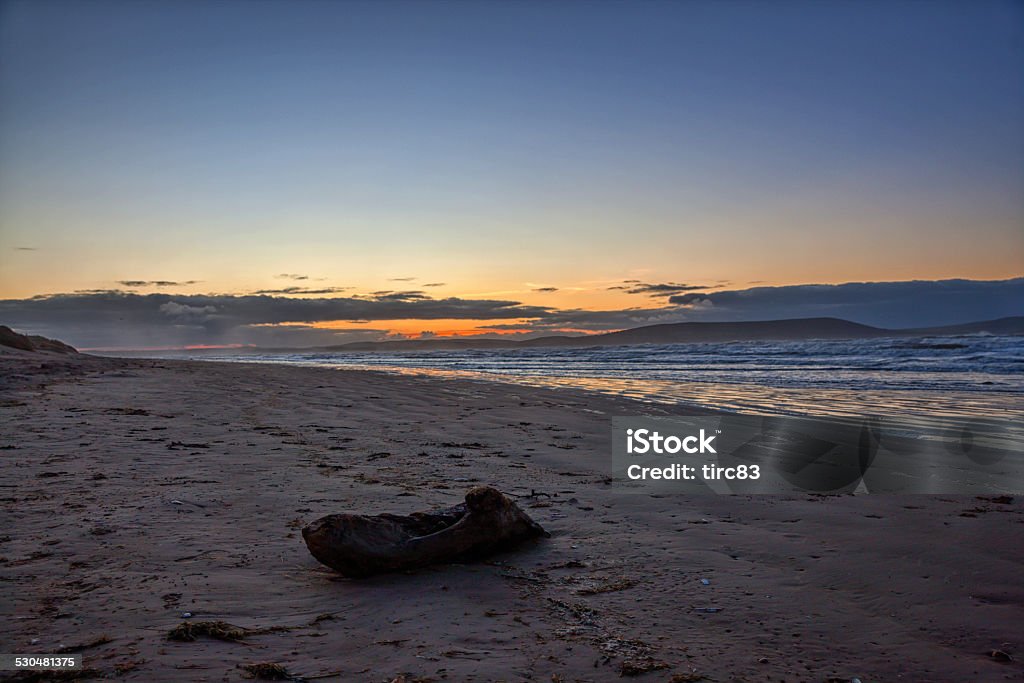 Footsteps in sand on beach at sunrise Back Lit Stock Photo