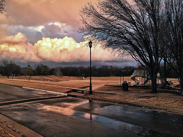 Colorful dramatic storm clouds are a street side backdrop tor a small park.