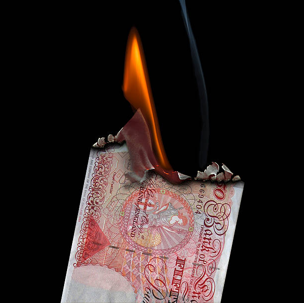 50 Pound Banknote on fire set on a  black background.