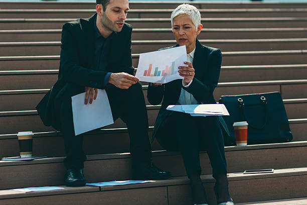 istock Businesspeople sitting on stairs and examining paperwork. 530484762