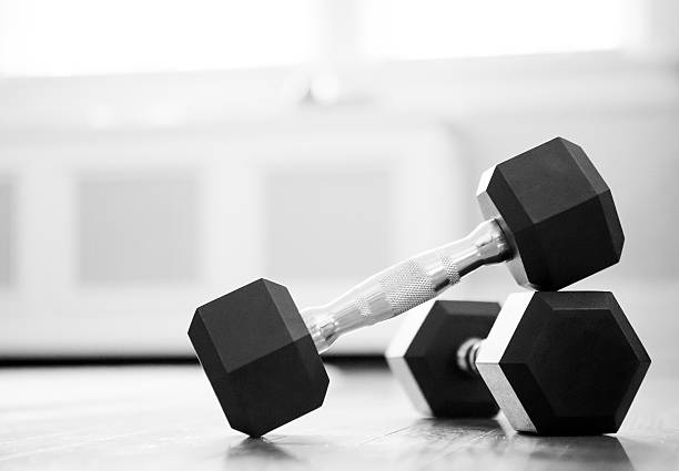 dumbbell close-up Close-up of dumbbells on the floor of home gym with sunlight through the window dumbbell photos stock pictures, royalty-free photos & images
