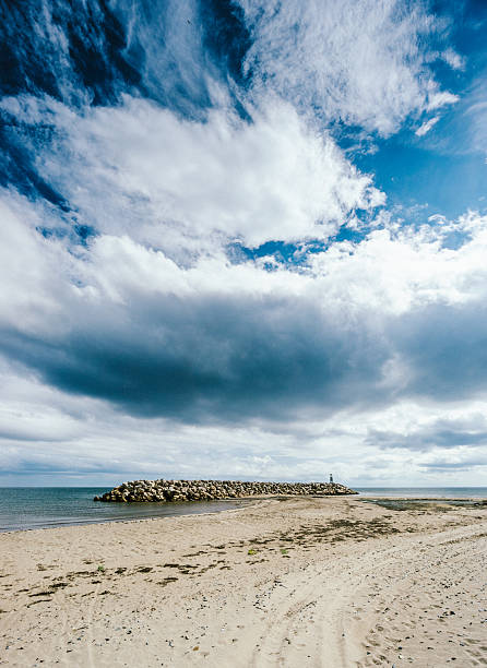 A glimpse at Pointe-Sapin harbour by the Atlantic ocean, in New Brunswick, Canada. A long rock pile is also visible in the image.