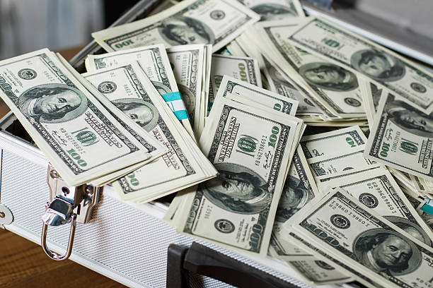 istock Suitcase with pile of dollars. 530491296