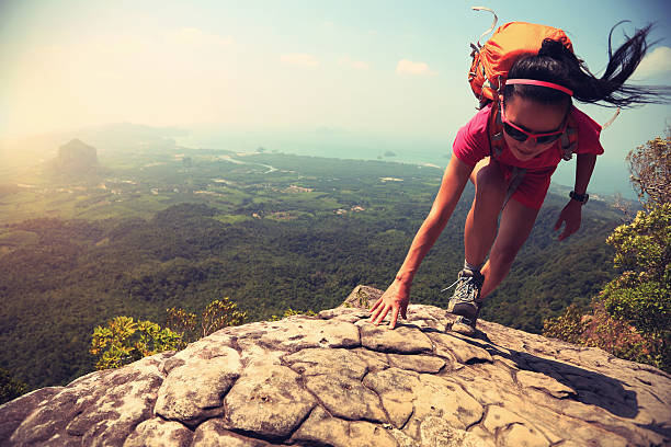 jeune asiatique femme de randonnée d'escalade sur falaise rocheuse sommet de la montagne - climbing mountain climbing rock climbing women photos et images de collection