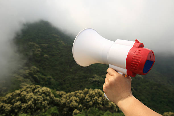 istock hand hold loudspeaker to blue sky on mountain peak 530493482
