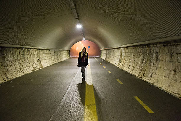 istock Young lady walks alone trough a tunnel in the dark 530493530