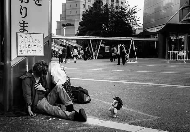 Tokyo, Japan - April 26, 2015: A street artist in Tokyo poses lifelessly with a cute toy.  The sign reads \