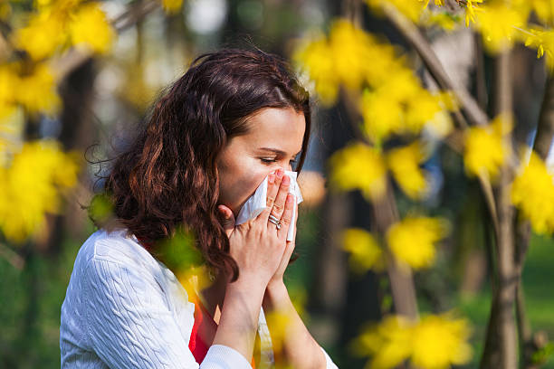 Woman with spring flu Young woman blowing her nose while being in the nature nose flower stock pictures, royalty-free photos & images