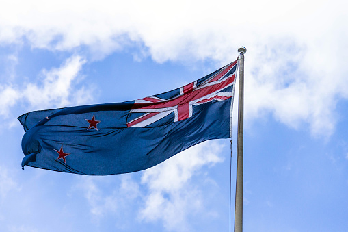 Australian flag waving against a blue sky with white clouds