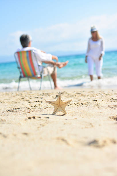 istock Sea stars on sand with couple in backgraund 530498308