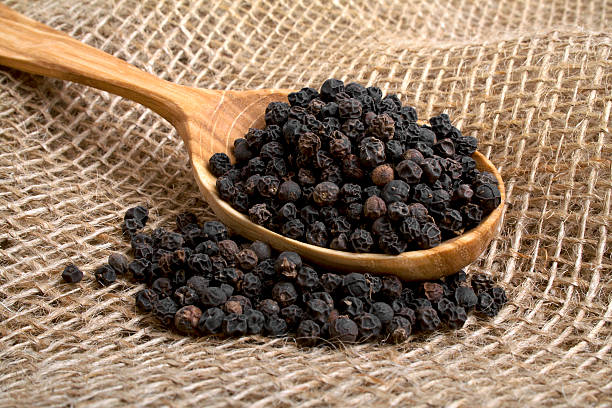 istock Black pepper in wooden spoon on burlap background 530502375