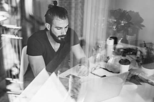 Black and white photo of handsome artist using laptop in his atelier