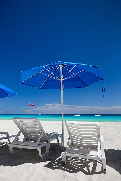 istock Caribbean beach with blue sun umbrellas and white beds 530505312