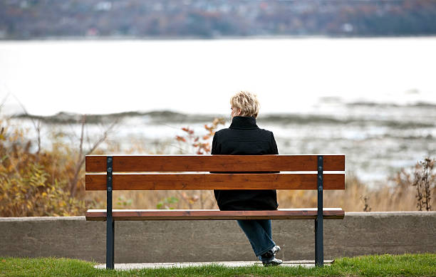 istock Woman sitting on bench overlooking river. 530507196