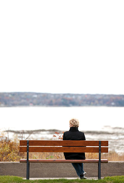 istock Woman sitting on bench overlooking river. 530507218
