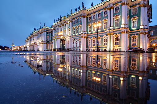 St. Petersburg, Russia - December 18, 2014: The building of the Winter Palace, which houses the Hermitage Museum at night illumination, reflected in the water paving puddle.