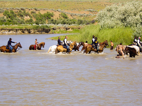 Crow Agency, Montana USA - June 27, 2009: Reenactment of the Battle of the Little Bighorn known as Custer's Last Stand. Young Indian warriors on horseback gallop across the river during battle reenactment.