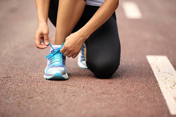 istock woman runner tying shoelaces on trail 530508257