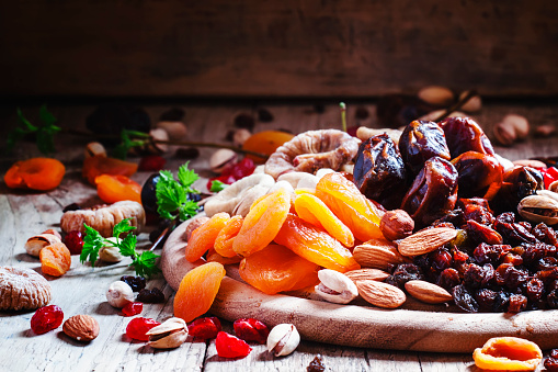Dried apricots, dates, raisins and various nuts, vintage wooden background, selective focus
