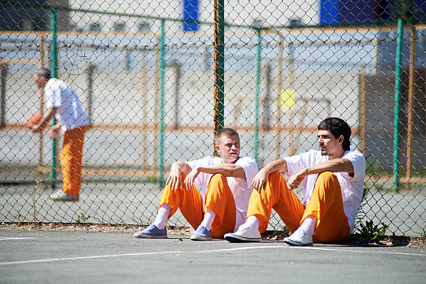 Behind the net Prisoners communicating during walk prisoner stock pictures, royalty-free photos & images