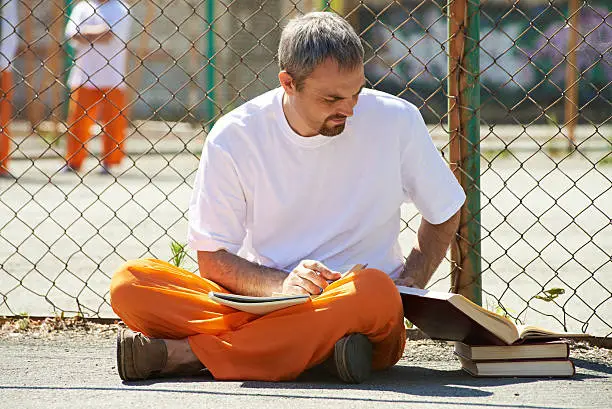 Man reading books at prison yard