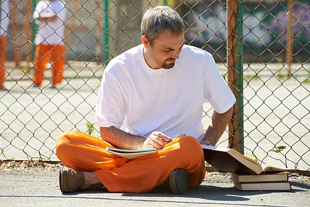 więzienia, student - men reading outdoors book zdjęcia i obrazy z banku zdjęć