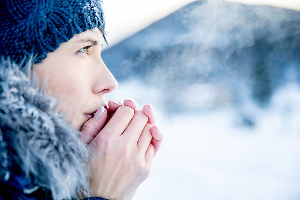 Young woman portrait on a cold winter day Young woman portrait on a cold winter day. Overcast and cold weather. She is heating her hands with her hot breath. breath vapor stock pictures, royalty-free photos & images