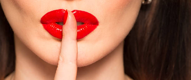 istock macro lips with red lipstick and finger showing hush 530519645
