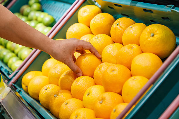 istock Hand holding orange in department store 530523867