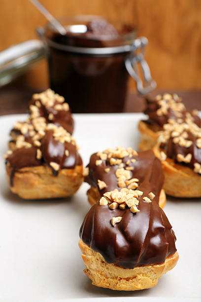 istock Eclairs with chocolate and nuts on plate on wooden background 530528455