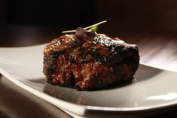 Partial view of man in a restaurant with a plate of steak and vegetables and two glasses of whiskey.