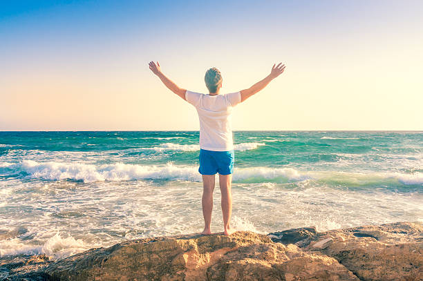 istock Man outdoors enjoying nature, raising hands 530548823