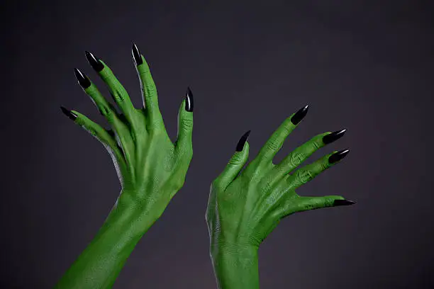 Green monster hands with black nails, Halloween theme, studio shot on black background