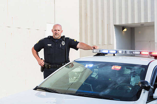 istock Serious police officer standing next to cruiser 530556071