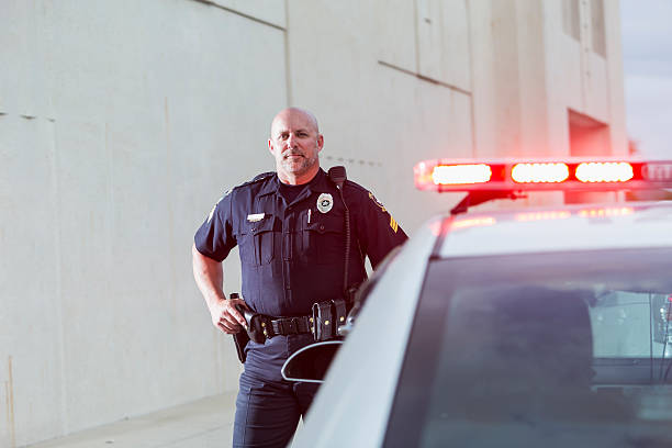 istock Serious police officer standing next to cruiser 530556105