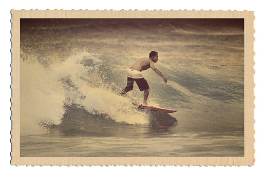 Retro 40s-50s style antique postcard with a surfer surfing the Pacific Ocean waves off the Hawaiian Island tropical beach of Kauai, Hawaii, USA. Surfing man image is an original photograph placed in an old postcard frame for this stock photo. It is not a scanned copy of an actual postcard.