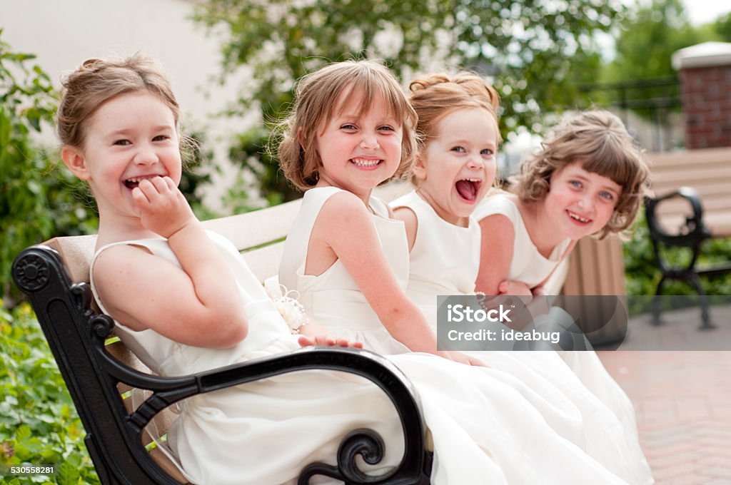 Four Happy Little Flower Girls Laughing Together in Formal Dresses Color photo of four happy little flower girls laughing together while wearing formal dresses. They are sisters and cousins. Wedding Stock Photo