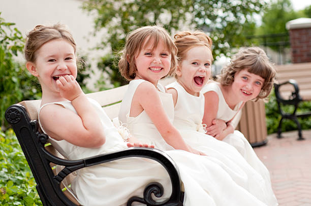 Four Happy Little Flower Girls Laughing Together in Formal Dresses Color photo of four happy little flower girls laughing together while wearing formal dresses. They are sisters and cousins. flower girl stock pictures, royalty-free photos & images