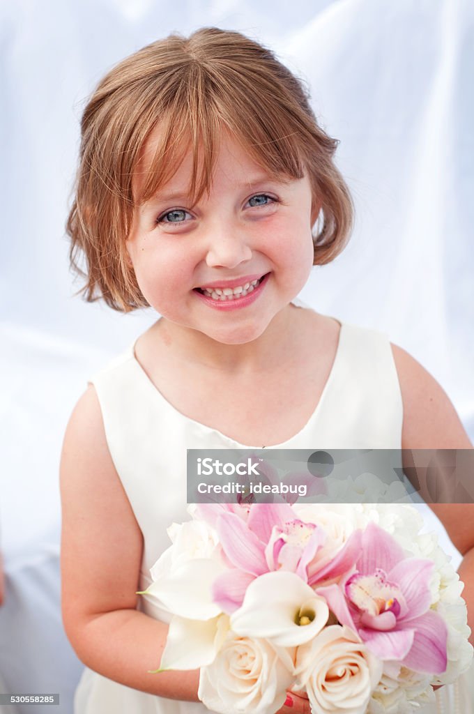 Happy Little Flower Girl in Formal Dress Color photo of a happy, little flower girl holding flowers while wearing a formal dress. Flower Girl Stock Photo