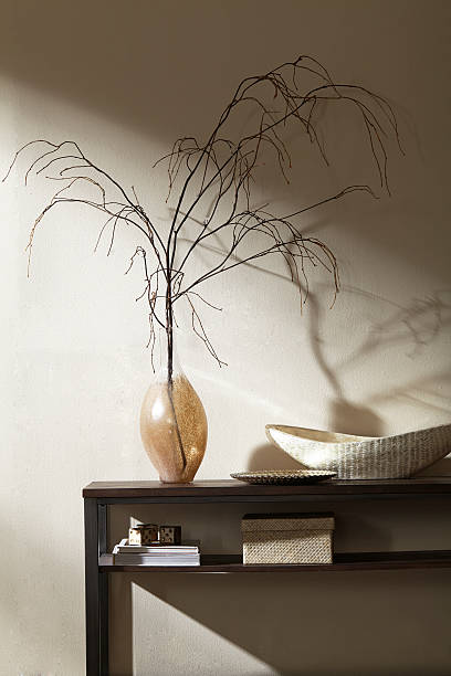 Still life of vase on table with branches.