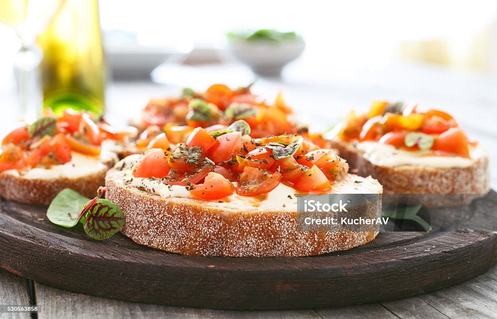 Sandwich with tomatoes, goat cheese and basil Sandwich with tomatoes, goat cheese and basil closeup. Delicious appetizer for wine Bruschetta Stock Photo