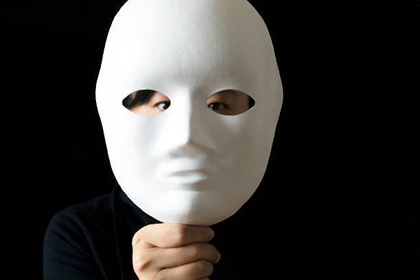 istock girl holding mask before face, in black backgrounds 530566752