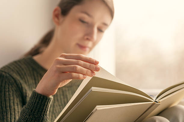 istock Close-up of female hands holding open book. 530566838