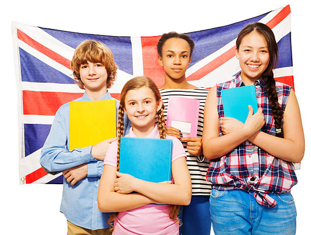 istock Four happy students standing against British flag 530569162